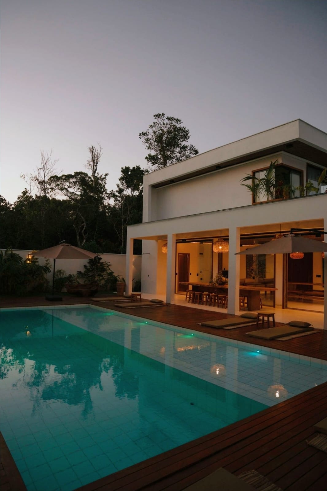 Fachada e piscina iluminadas ao anoitecer